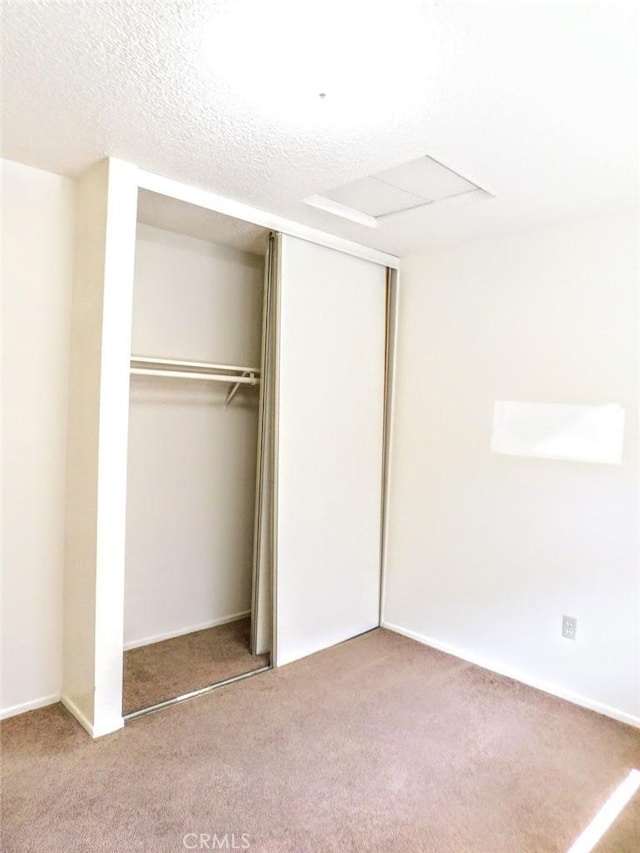 unfurnished bedroom featuring a textured ceiling, carpet floors, and a closet