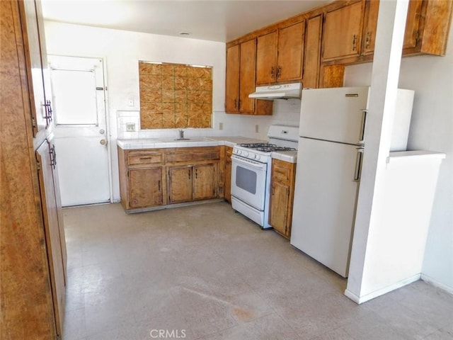 kitchen with light countertops, white appliances, brown cabinets, and under cabinet range hood