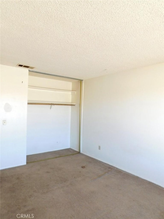 unfurnished bedroom with a textured ceiling, a closet, and visible vents