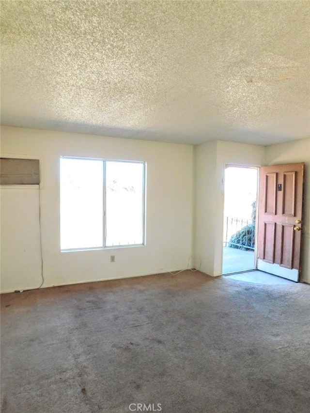 carpeted spare room with a textured ceiling and a wall mounted air conditioner