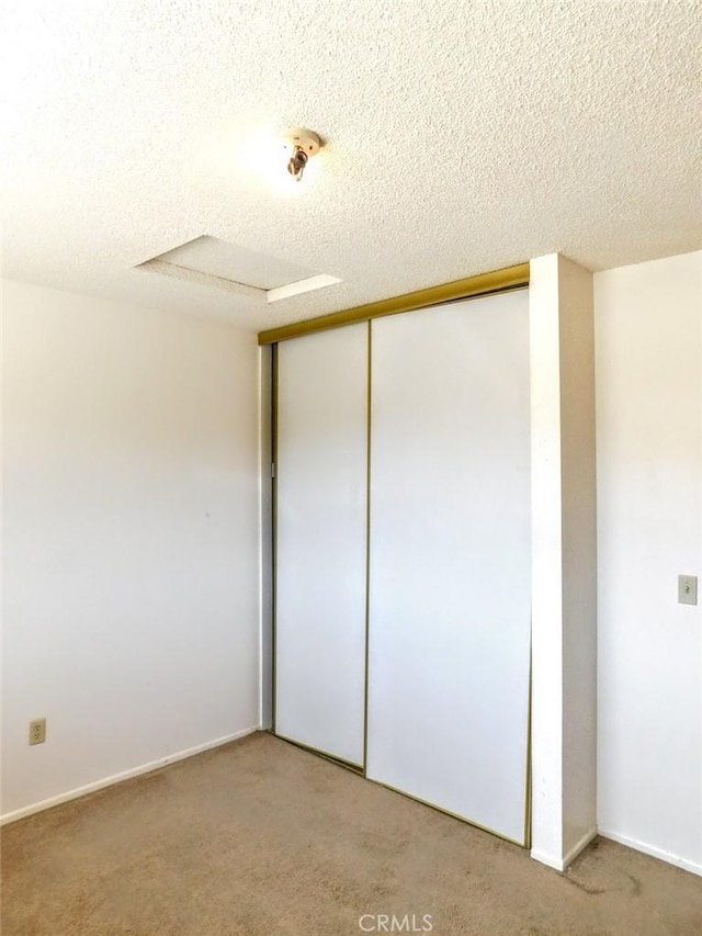 unfurnished bedroom with carpet, a closet, and a textured ceiling