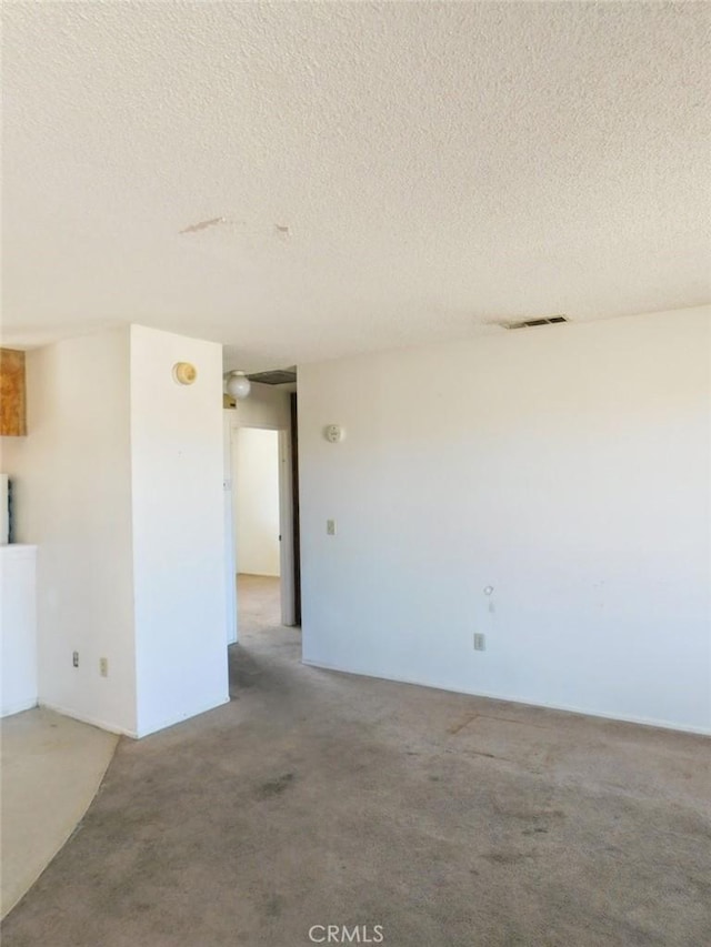 carpeted spare room with a textured ceiling and visible vents