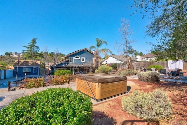 view of yard featuring a hot tub, a fenced backyard, and an outbuilding