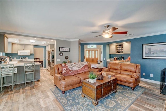 living room featuring visible vents, a ceiling fan, baseboards, ornamental molding, and light wood-type flooring