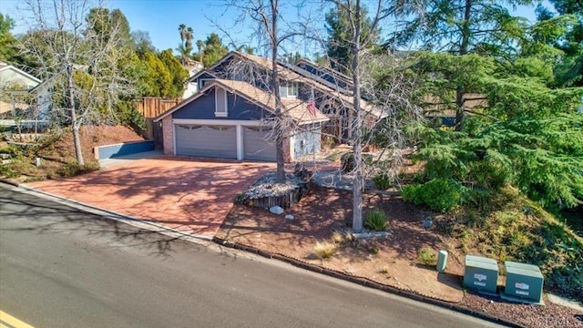 view of front of home with driveway, an attached garage, and fence