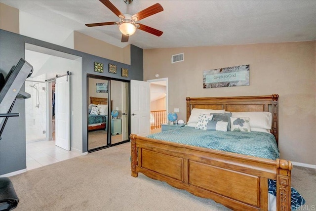 bedroom featuring lofted ceiling, ceiling fan, a barn door, light colored carpet, and visible vents