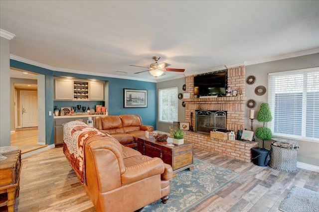 living room featuring baseboards, light wood-type flooring, a brick fireplace, and crown molding