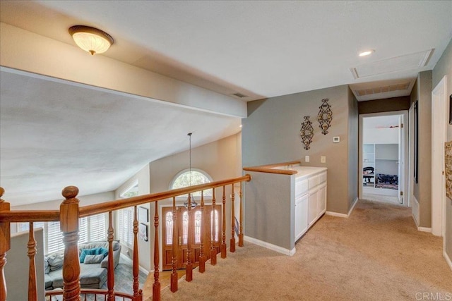 hallway with light carpet, baseboards, and vaulted ceiling