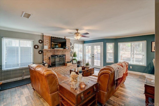 living area featuring crown molding, visible vents, a fireplace, and light wood finished floors