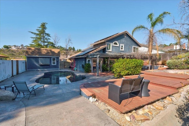 view of swimming pool with a fenced backyard, a deck, a fenced in pool, and an outbuilding