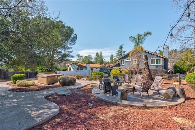 view of yard featuring an outdoor fire pit, a hot tub, fence, and a patio