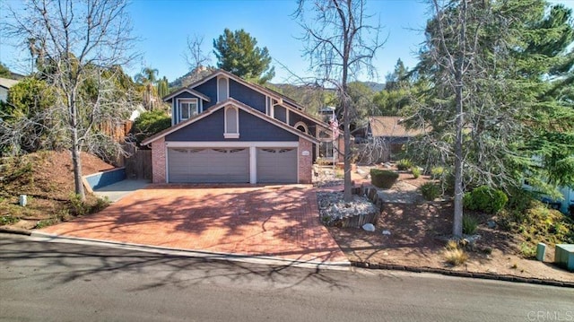 view of front facade with a garage, decorative driveway, and brick siding