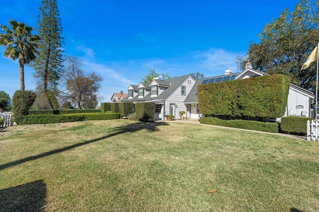 view of front of property with a front yard and roof mounted solar panels