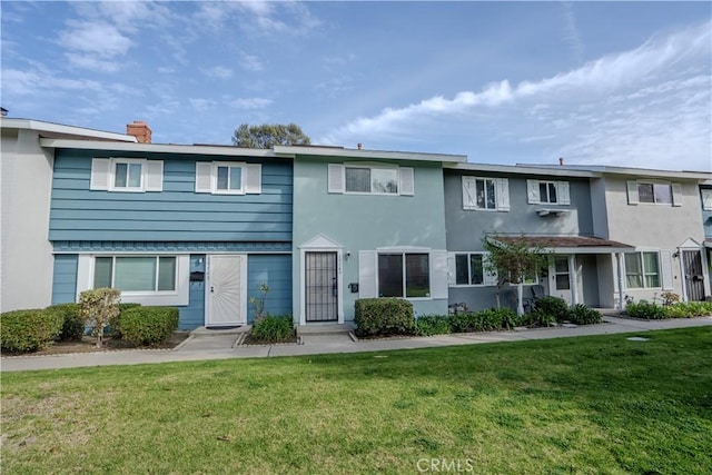 townhome / multi-family property featuring stucco siding, a chimney, and a front yard