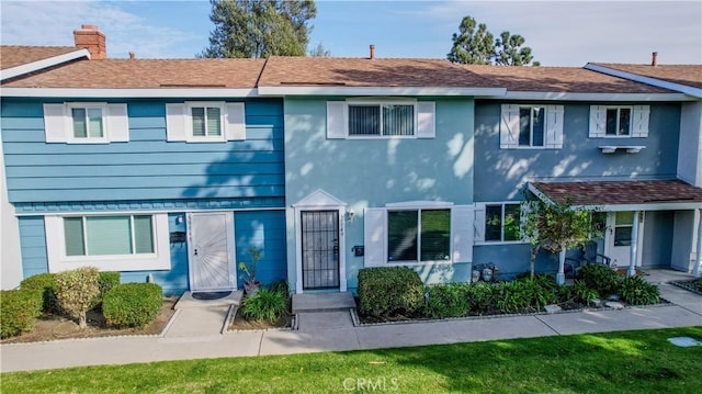 townhome / multi-family property featuring roof with shingles and a chimney