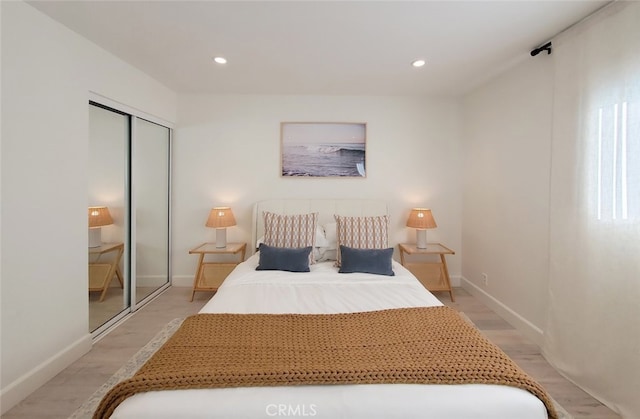 bedroom with a closet, recessed lighting, light wood-style flooring, and baseboards