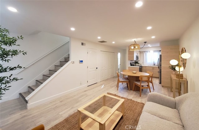 living room featuring light wood-type flooring, stairway, visible vents, and recessed lighting