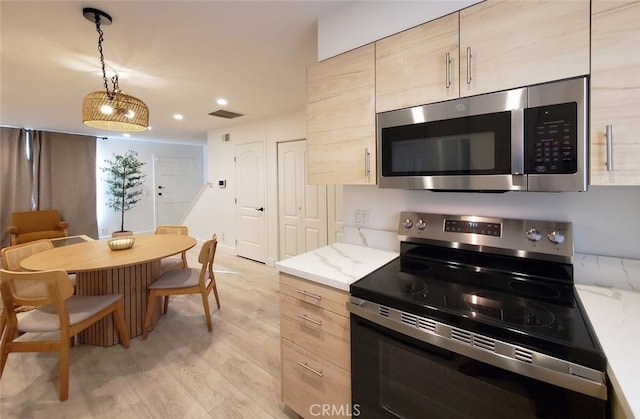 kitchen featuring visible vents, light brown cabinetry, light wood-type flooring, appliances with stainless steel finishes, and hanging light fixtures