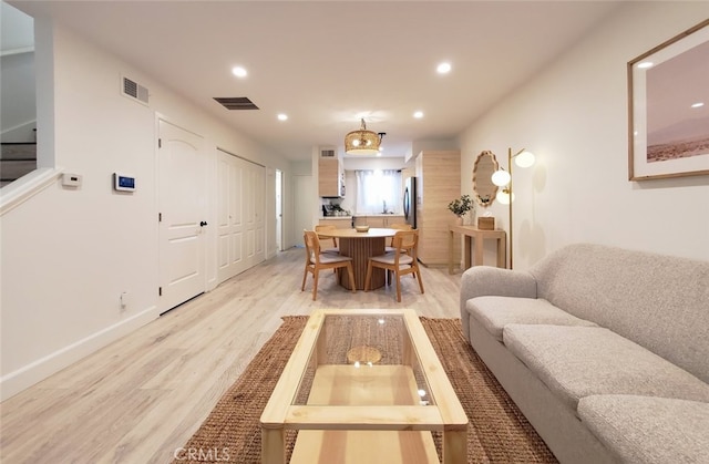 living area with light wood-style flooring, recessed lighting, visible vents, and baseboards