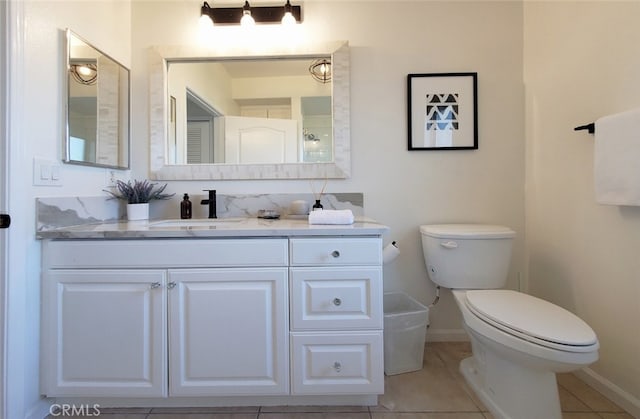 bathroom featuring tile patterned flooring, baseboards, toilet, and vanity