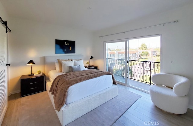 bedroom with access to outside and wood finished floors