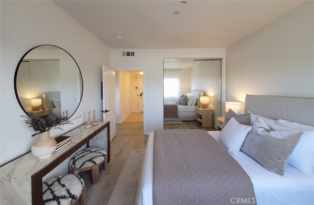 bedroom featuring visible vents, light wood finished floors, and a closet