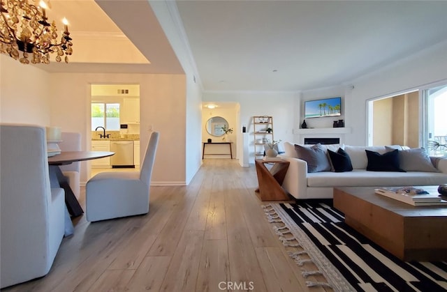 living room with crown molding, light wood finished floors, a chandelier, baseboards, and visible vents