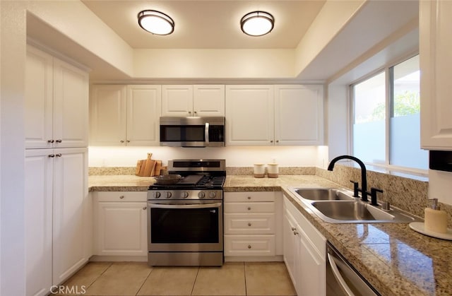 kitchen featuring a sink, appliances with stainless steel finishes, light tile patterned floors, and white cabinets