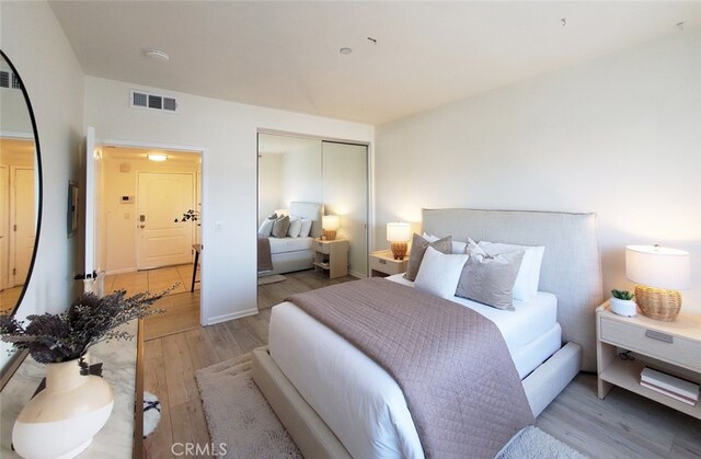 bedroom with visible vents, light wood finished floors, and a closet