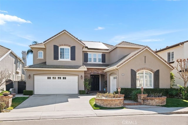 traditional-style house with an attached garage, solar panels, a tile roof, driveway, and stucco siding