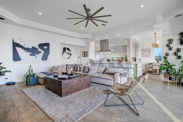 living room with a chandelier, recessed lighting, light wood-style flooring, and a tray ceiling