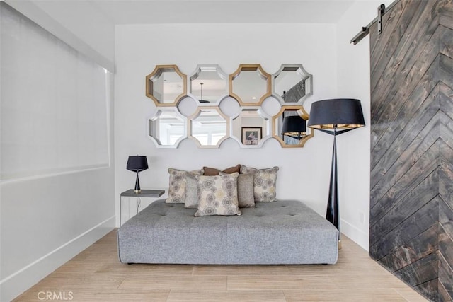 bedroom with light wood-type flooring, a barn door, and baseboards