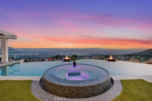 view of swimming pool with an outdoor fire pit and a pool with connected hot tub