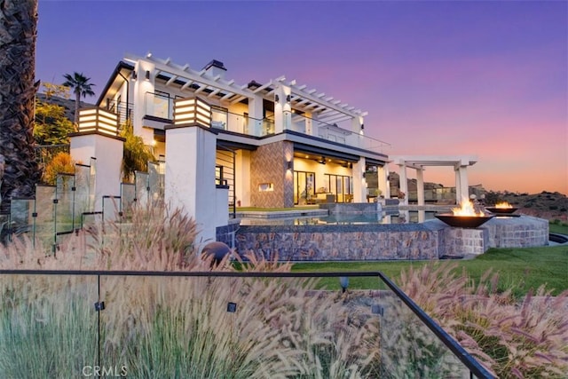 view of front of home with a fire pit, a balcony, and stucco siding