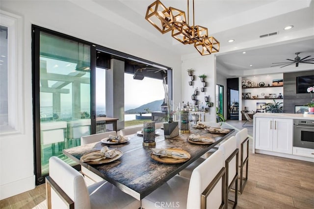 dining area featuring light wood-style floors, recessed lighting, visible vents, and ceiling fan with notable chandelier