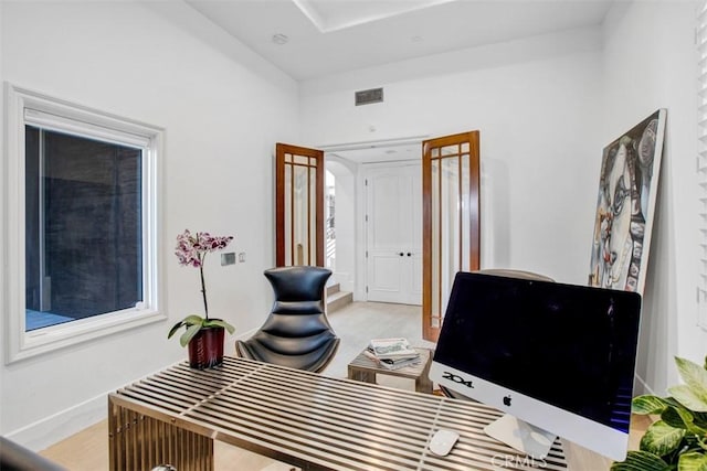 home office with light wood finished floors, visible vents, and baseboards