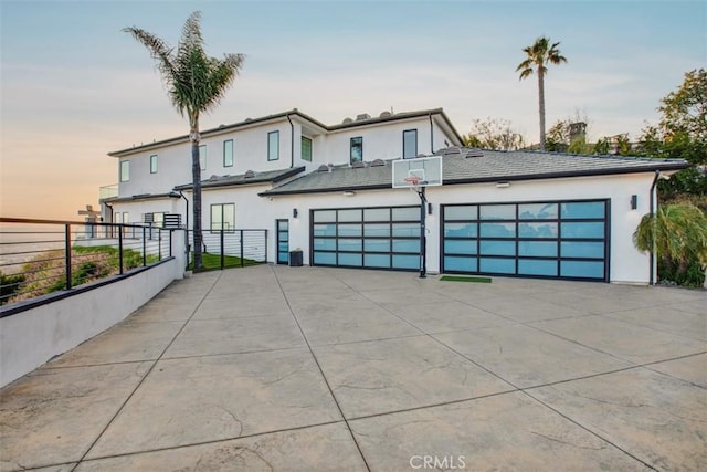 view of front of property featuring driveway, an attached garage, fence, and stucco siding