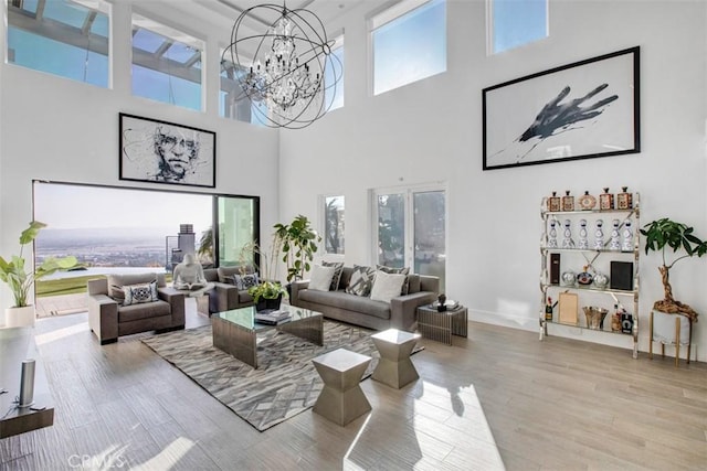 living room featuring baseboards, plenty of natural light, light wood finished floors, and an inviting chandelier