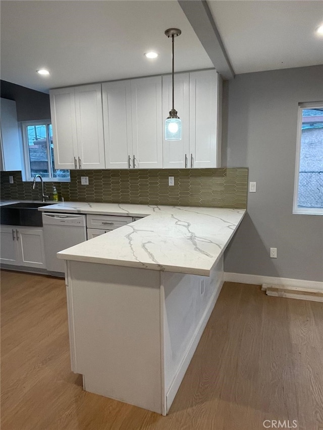 kitchen with light stone counters, decorative light fixtures, white cabinetry, white dishwasher, and a peninsula