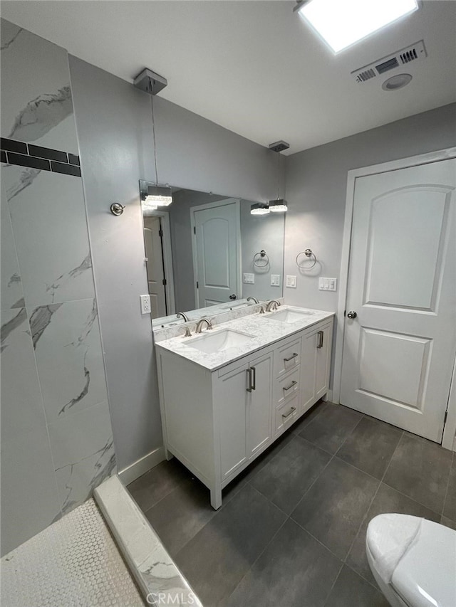 full bath featuring toilet, double vanity, a sink, and visible vents