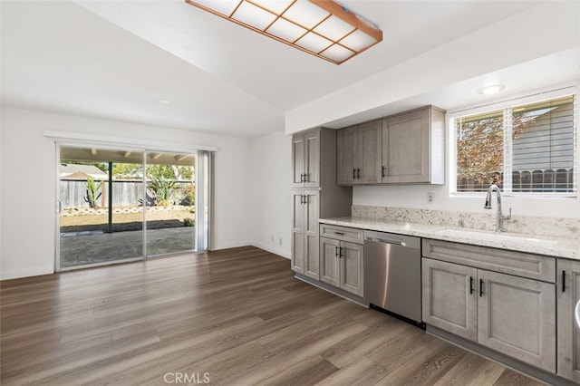 kitchen featuring light stone counters, a sink, dark wood-style floors, vaulted ceiling, and dishwasher