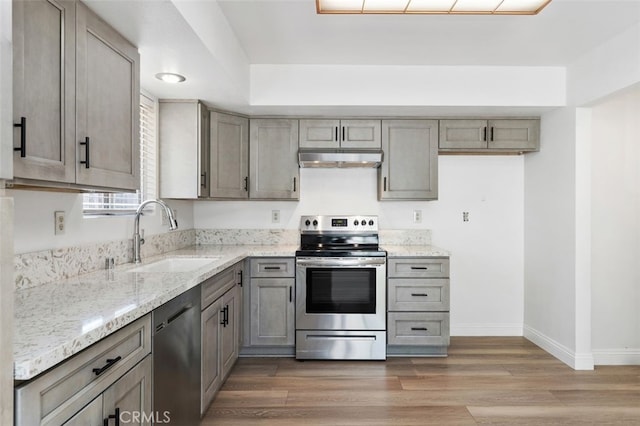 kitchen featuring under cabinet range hood, a sink, electric stove, light wood-type flooring, and dishwasher