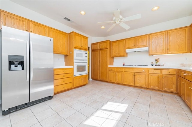 kitchen featuring light countertops, white appliances, visible vents, and under cabinet range hood