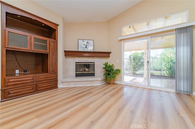 unfurnished living room featuring a tile fireplace and wood finished floors