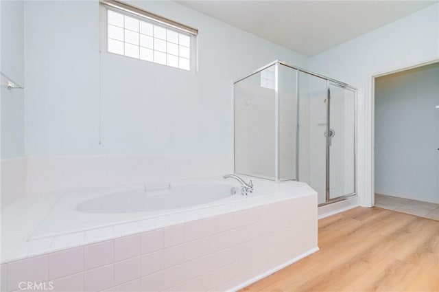 bathroom with a bath, a stall shower, and wood finished floors