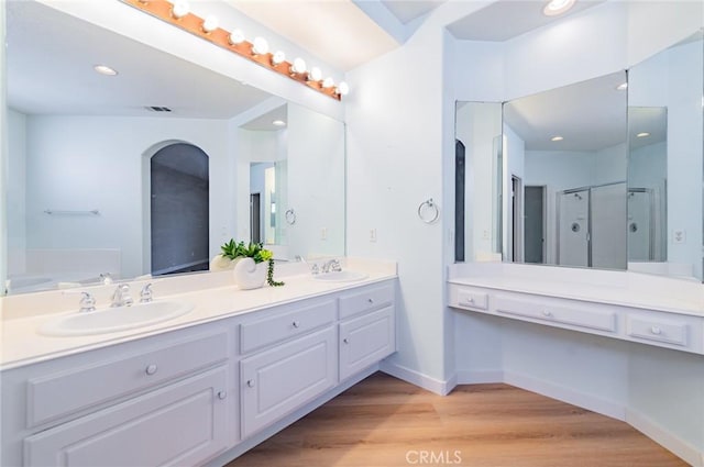 full bathroom with visible vents, a sink, wood finished floors, double vanity, and baseboards