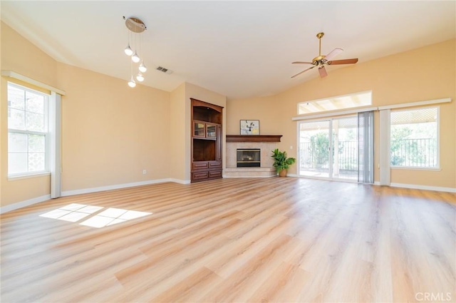 unfurnished living room featuring a ceiling fan, visible vents, baseboards, light wood-type flooring, and a glass covered fireplace