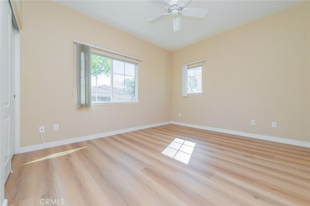 empty room with a ceiling fan, light wood-type flooring, and baseboards