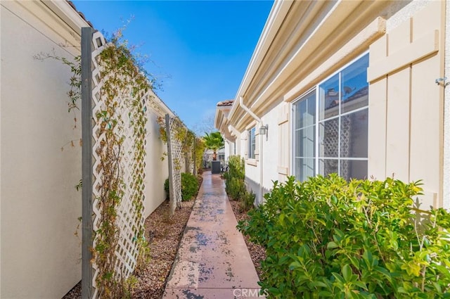 view of side of home with stucco siding and fence