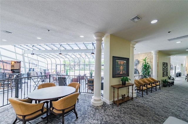 dining space with visible vents, a textured ceiling, carpet flooring, and ornate columns